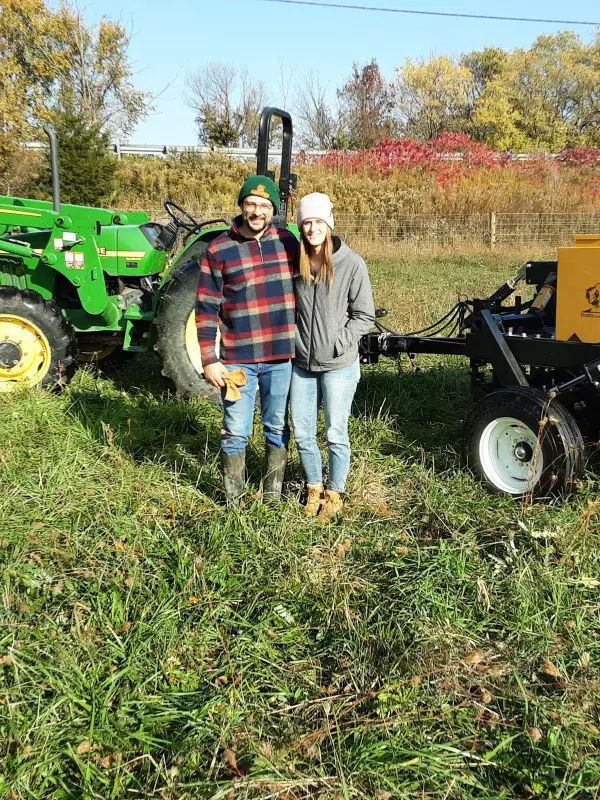 A couple pose in front of a tractor