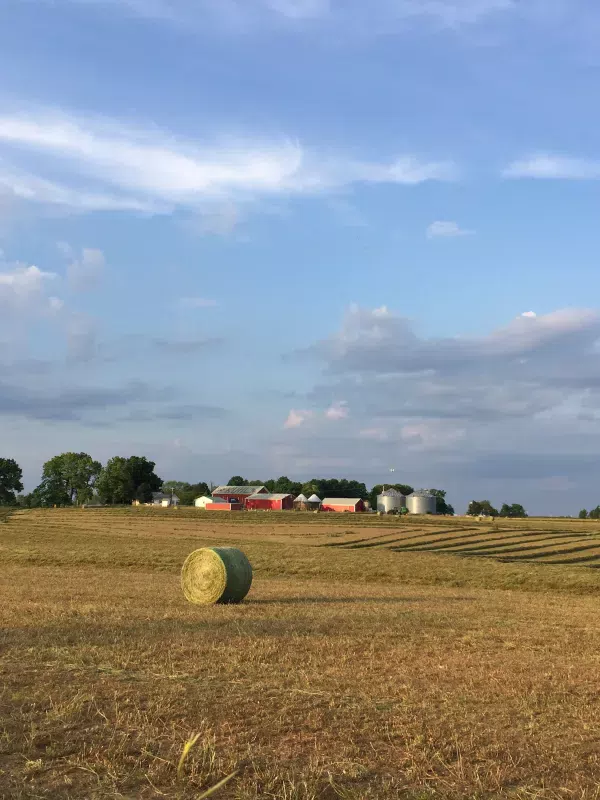 photo of farm in dance with hay bail in foreground