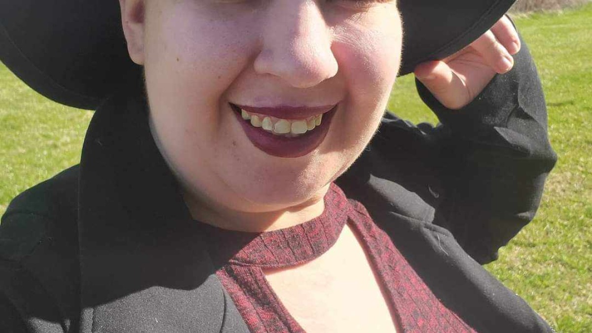 Owner in Nature wearing black hat and jacket with red dress.