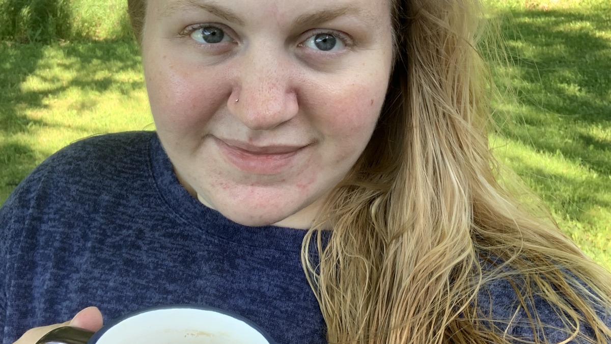 Young adult woman holding cup of coffee outside enjoying life.