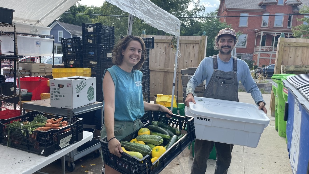 Magda and Zach hold bins of vegetables for delivery.