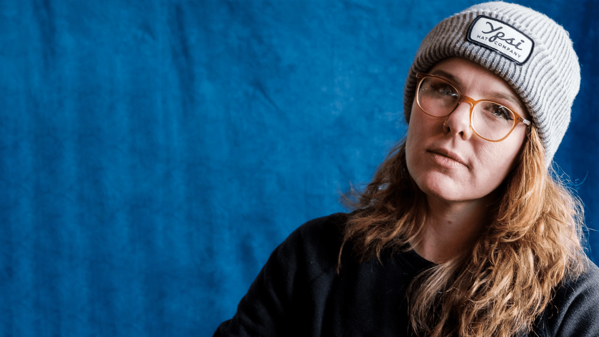 Photo shows a woman with glasses, red hair, and a gray Ypsi Hat Company beanie.