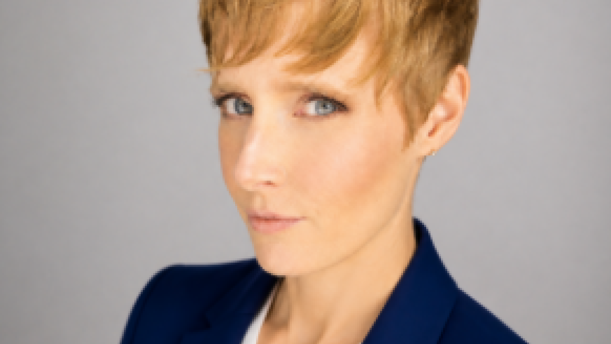 Professional photo — woman with a pixie cut, in a white blouse and blue blazer.
