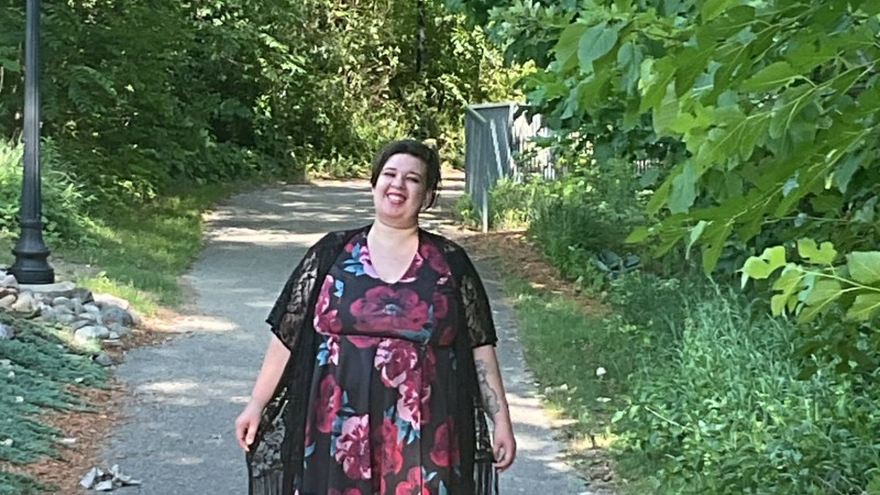 Woman (ower) standing a flower dress in nature on a trail