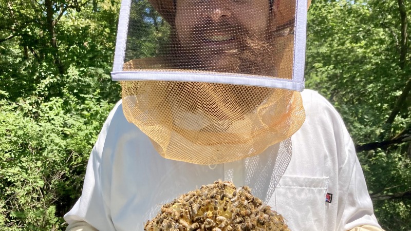 A photo of a farmer holding a bee hive
